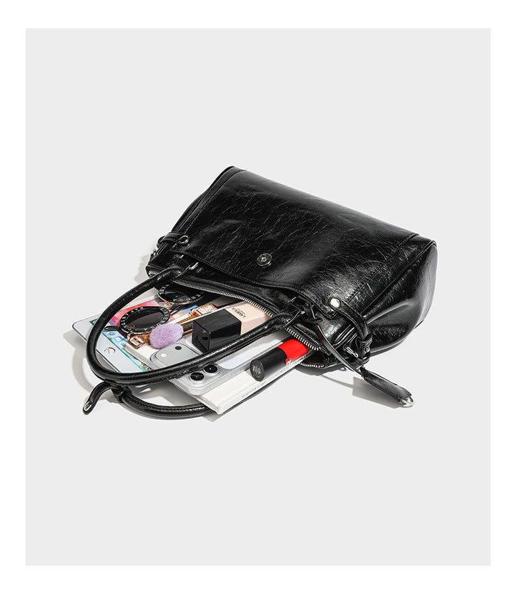 Structured glossy crinkled leather-look satchel with double top handles, front metal-plaque tab, silver-tone hardware, and
