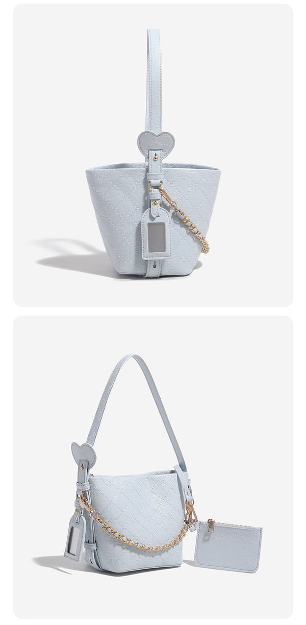 Small diamond-quilted bucket bag with gold-tone chain accent, heart strap detail, hanging tag, and matching zip coin pouch