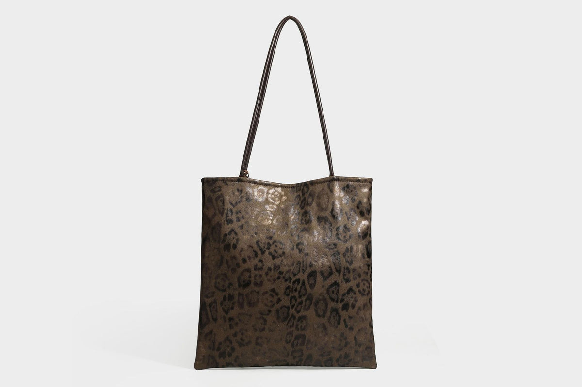 Large leopard print shoulder tote bag in tan and brown with slim dark straps and dangling beaded charm hardware, detail view