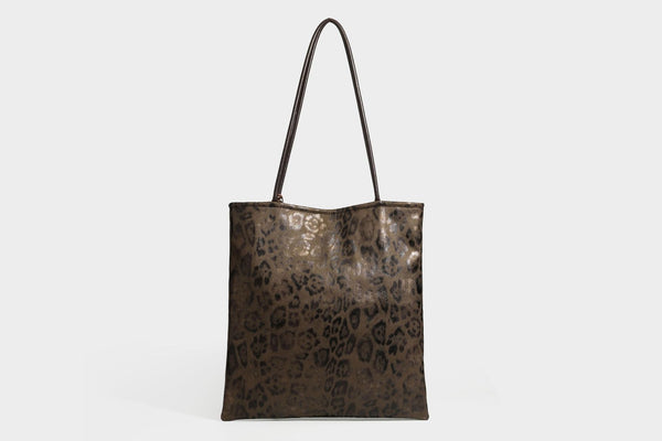 Large leopard print shoulder tote bag in tan and brown with slim dark straps and dangling beaded charm hardware, detail view