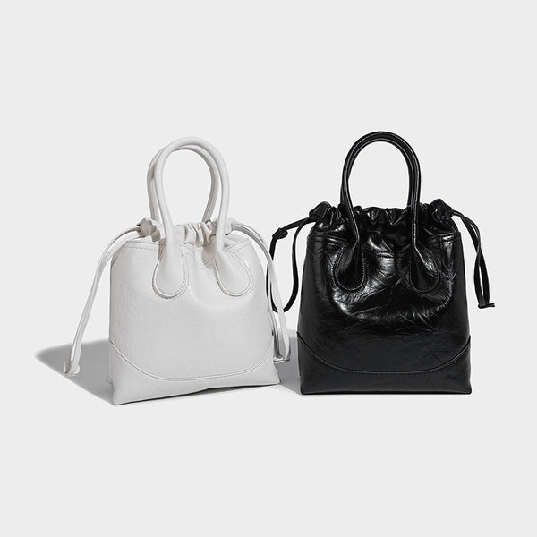 Glossy crinkled ruched drawstring bucket bag with rounded double top handles and detachable chain crossbody strap, detail
