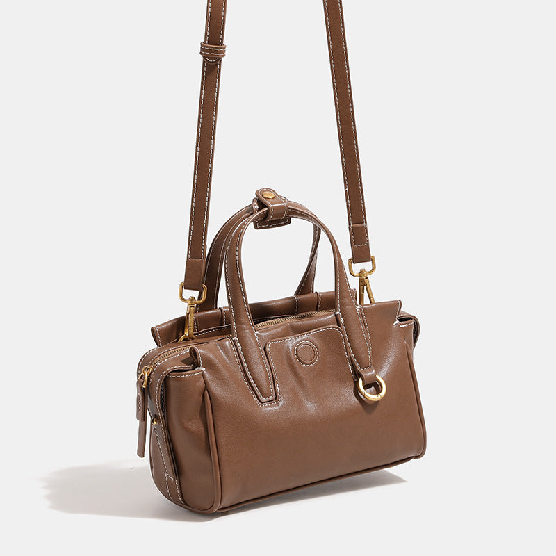 Compact structured satchel bag with dual top handles, gold-tone O-ring hardware, contrast topstitching, and detachable