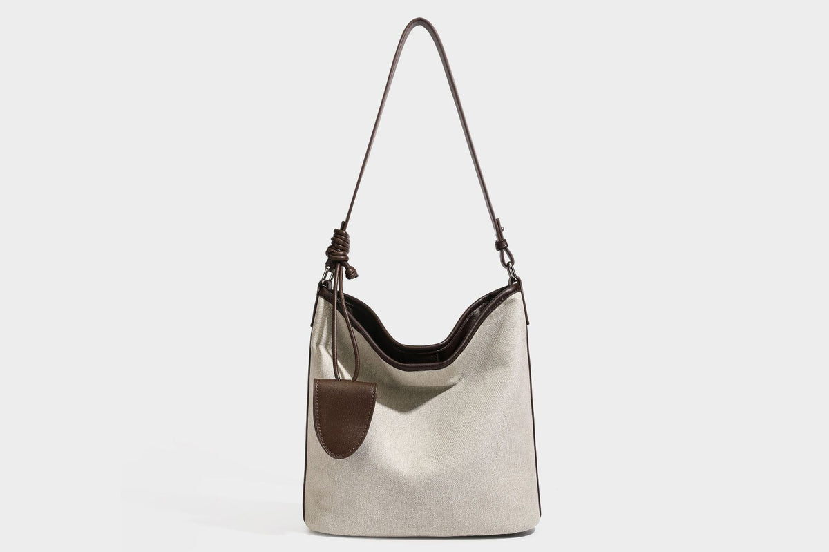 Oatfarbene Canvas-Schultertasche mit dunkelbraunem Besatz in Lederoptik, langem verstellbarem Riemen und angebrachter Mini-Tasche mit Überschlag, Detailansicht