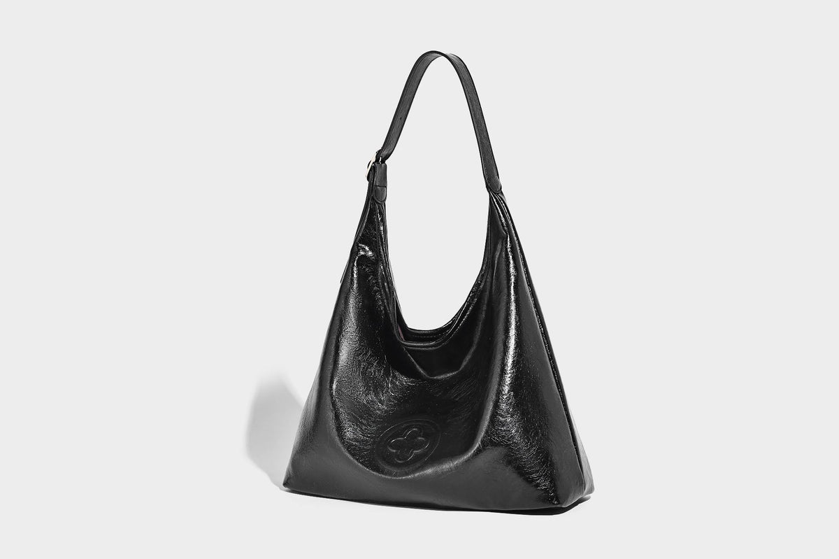 Glossy slouchy hobo shoulder bag with adjustable strap and embossed floral emblem, detail view 12