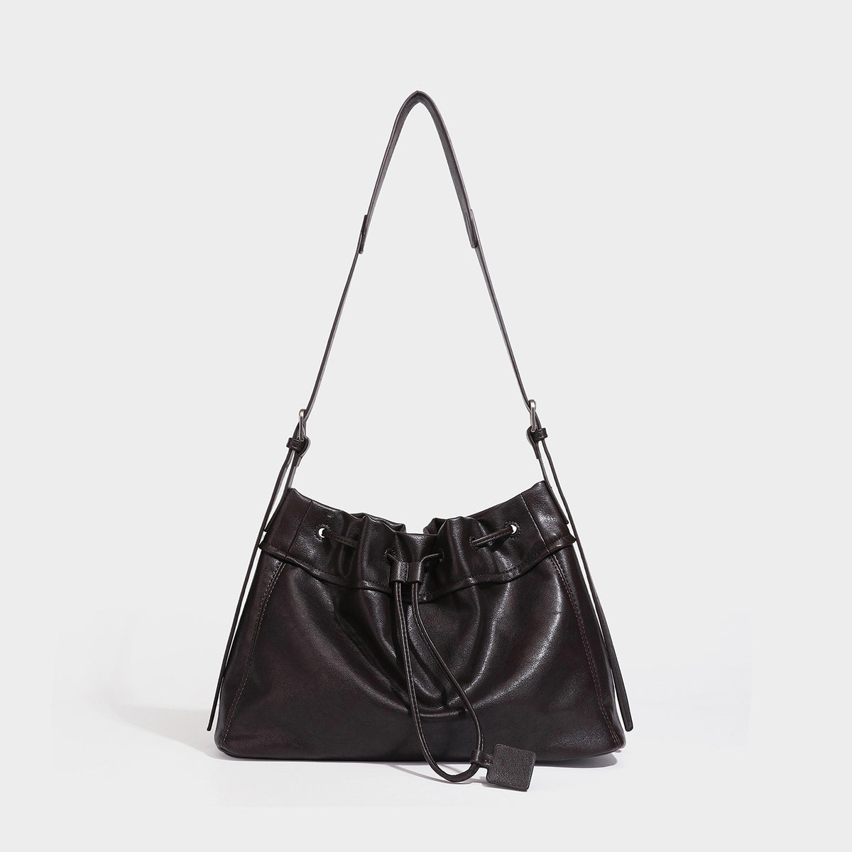 Slouchy drawstring bucket bag in dark brown leather-look finish with long adjustable shoulder strap and gathered tie closure