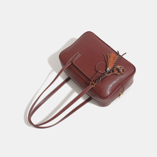 Structured rectangular leather-look shoulder bag with top zip, tassel and resin ring charm, and contrast topstitching, detail