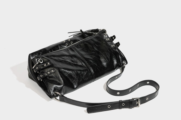 Black glossy leather-look slouchy shoulder bag with silver stud and eyelet hardware, top zip closure, front zip pocket, and