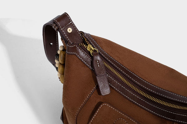 Matte Hobo-Schultertasche in warmem Braun mit dunklem Besatz in Lederoptik, Kontrastnähten, goldfarbenen Metallbeschlägen und