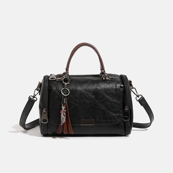 Compact structured barrel bag in distressed leather-look finish with dual top handles, detachable crossbody strap, front zip