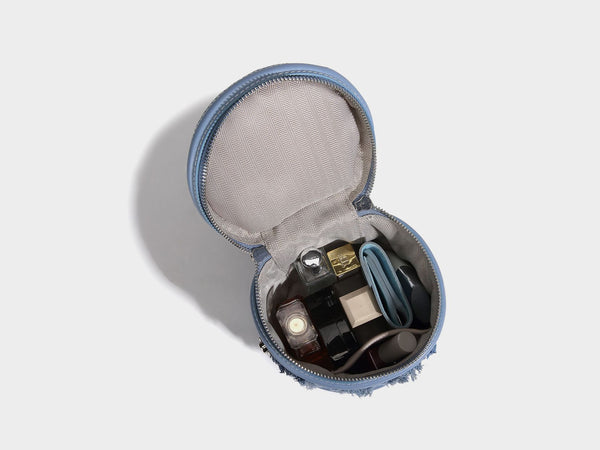 Mini cylindrical barrel bucket bag in denim patchwork with frayed edges, smooth leather-look trim, zip-around top closure