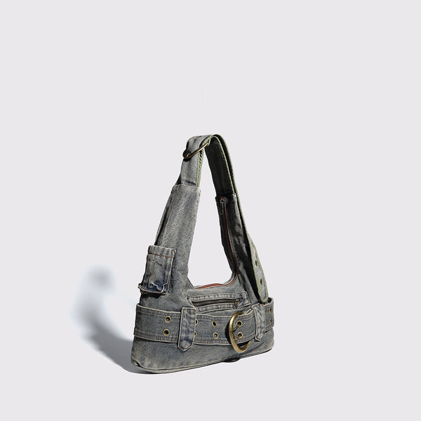 Washed faded denim hobo shoulder bag with wide brass-tone buckle belt panel, eyelet detailing, front zip pocket, and dual