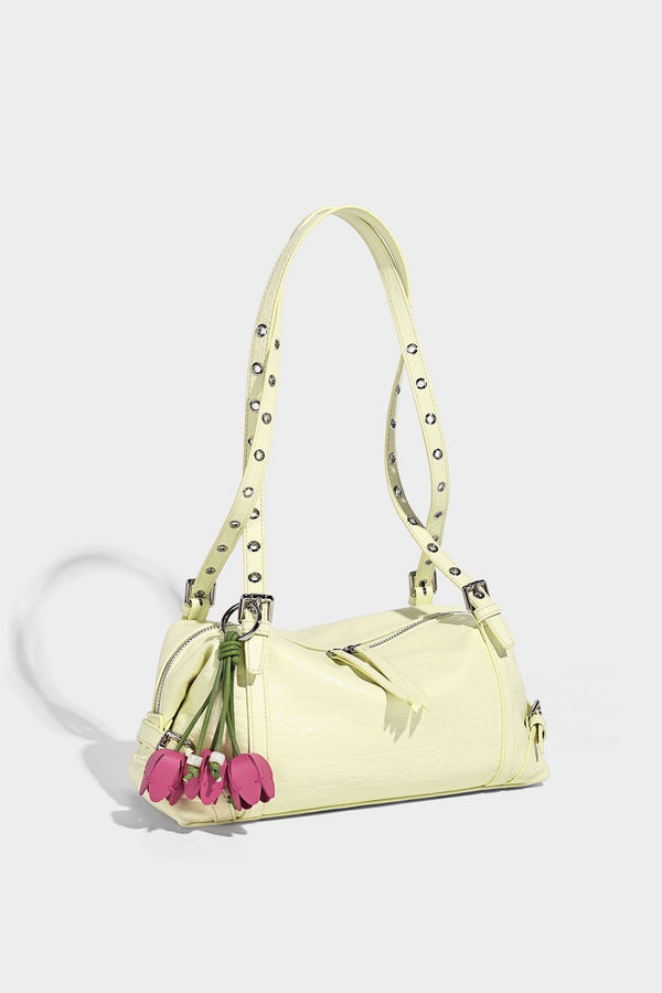 Pale yellow leather-look barrel bag with silver grommet-studded shoulder straps, top zip closure, and pink tulip floral