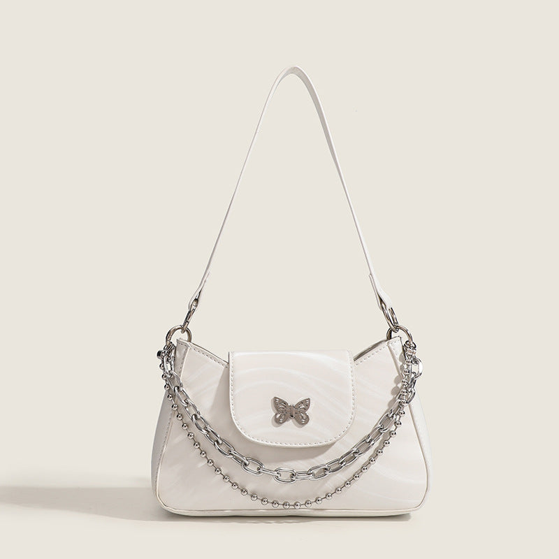 Small trapezoid shoulder bag with ripple leather-look finish, silver butterfly front clasp, and layered chain-and-ball strap