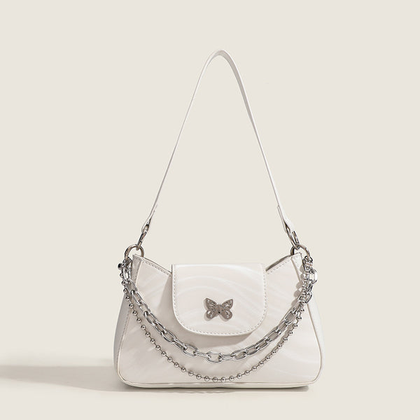Small trapezoid shoulder bag with ripple leather-look finish, silver butterfly front clasp, and layered chain-and-ball strap