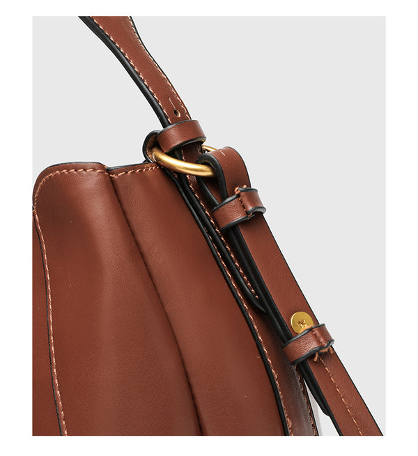 Smooth leather-look paneled bucket bag in brown with wide woven shoulder strap, gold-tone ring hardware, and detachable zip