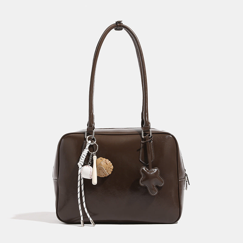 Large glossy leather-look Boston bag with double top handles, front star appliqué, and detachable baseball charm set, detail