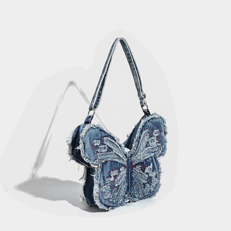 Butterfly-shaped distressed denim shoulder bag with frayed raw edges and embroidered wing panels, detail view 3