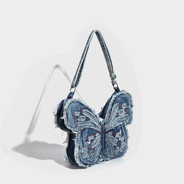 Butterfly-shaped distressed denim shoulder bag with frayed raw edges and embroidered wing panels, detail view 3