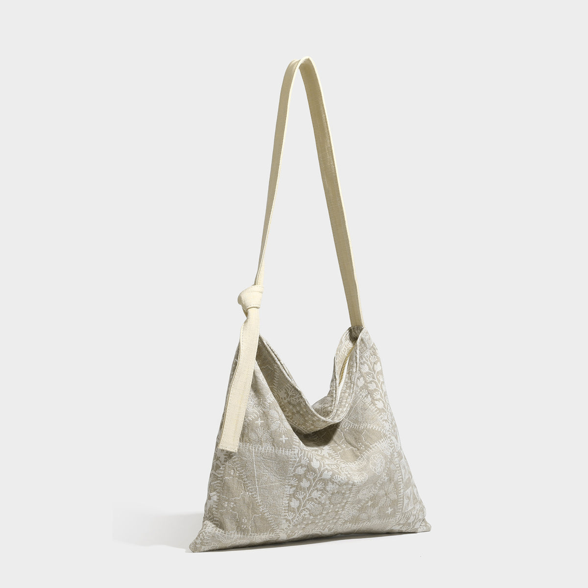 Lässig geschnittene Hobo-Schultertasche aus Canvas mit botanischem Print, langem geknotetem Trageriemen und Reißverschluss oben, Vorderansicht
