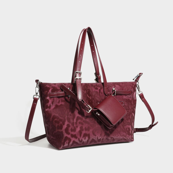 Glossy leopard-print tote bag with leather-look dark trim, dual top handles, detachable shoulder strap, and attached front