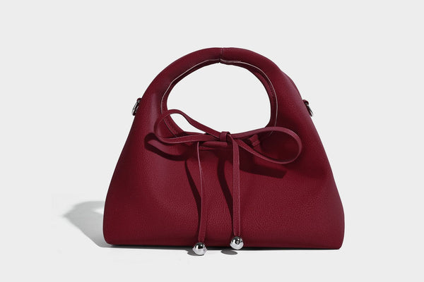 Pebbled matte trapezoid top-handle bag with drawstring bow closure, bead-tipped cords, silver-tone hardware, and detachable