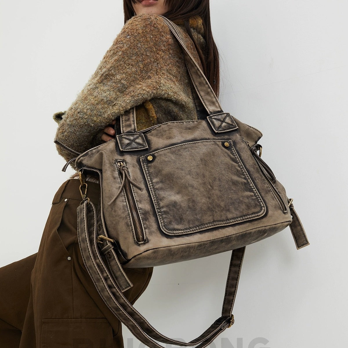 Distressed leather-look convertible tote bag with dual top handles, front zip and patch pockets, and adjustable shoulder