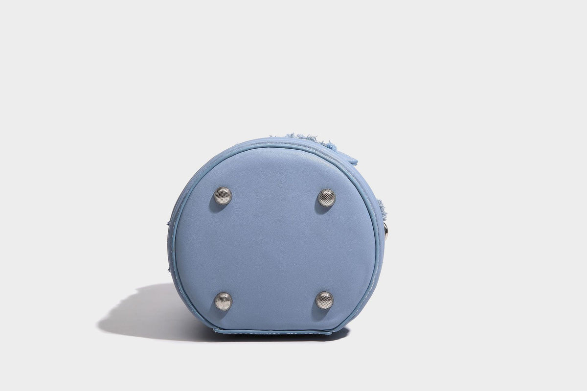 Mini cylindrical barrel bucket bag in denim patchwork with frayed edges, smooth leather-look trim, zip-around top closure