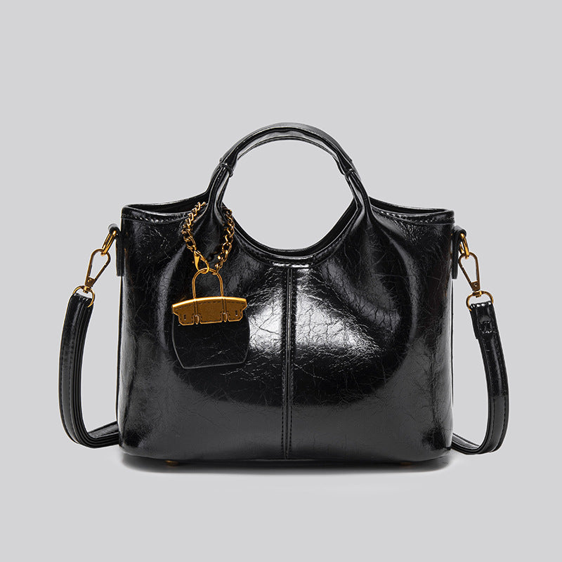 Structured crinkle-gloss top-handle satchel in deep burgundy with antique gold lock charm and detachable shoulder strap
