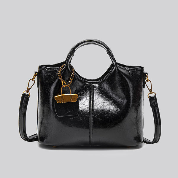 Structured crinkle-gloss top-handle satchel in deep burgundy with antique gold lock charm and detachable shoulder strap