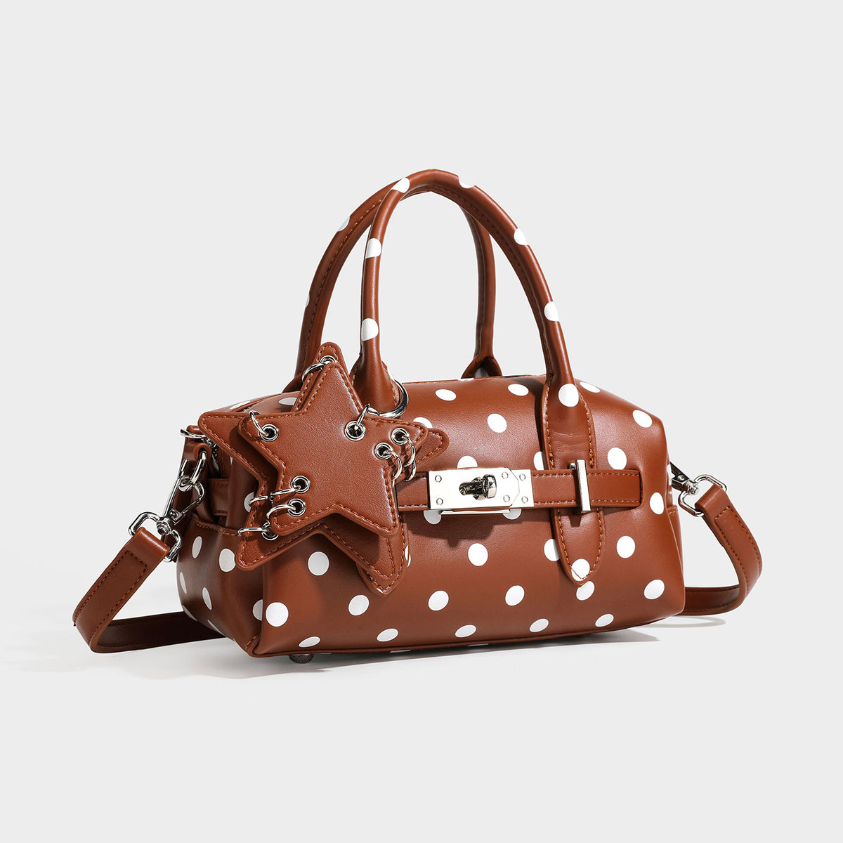 Small structured polka-dot mini satchel bag with star charm, buckle-strap front detail, dual top handles, and detachable