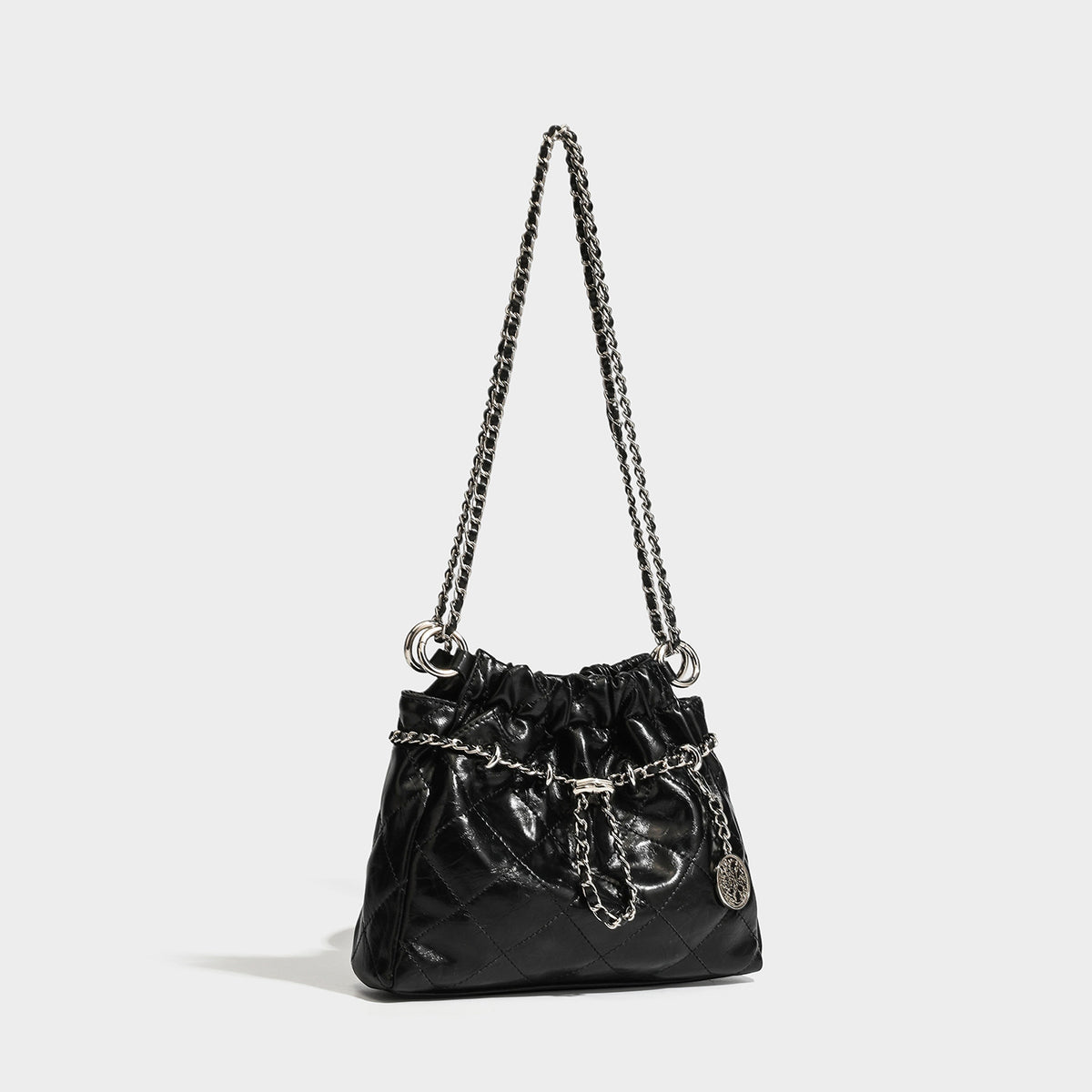Glossy diamond-quilted drawstring bucket bag with silver chain shoulder strap and medallion charm, front view