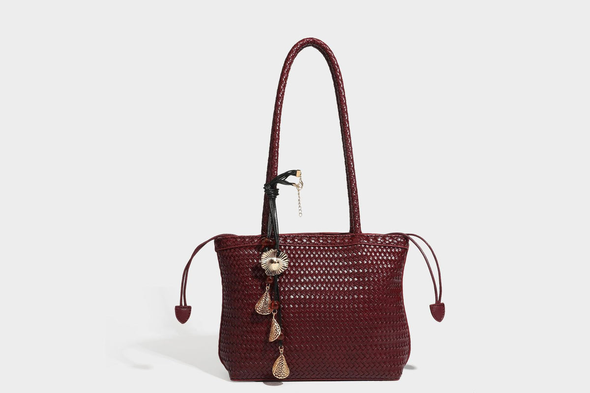Structured woven leather-look tote bag in dark brown with long shoulder straps, side drawstring ties, and gold filigree
