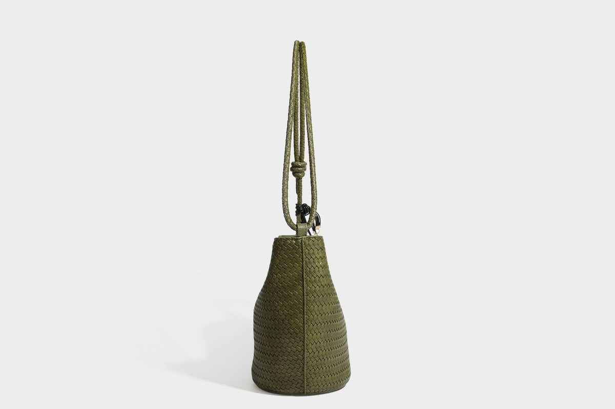 Olive green woven leather-look bucket bag with braided crossbody strap, knotted adjustment, and gold-tone tassel charm with