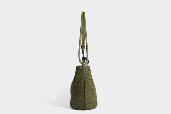 Olive green woven leather-look bucket bag with braided crossbody strap, knotted adjustment, and gold-tone tassel charm with