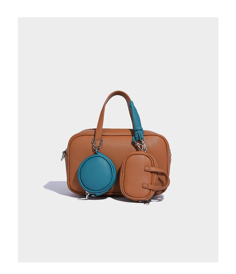 Structured pebbled leather-look Boston bowling bag in tan with blue detachable round mini pouch, dual top handles, and