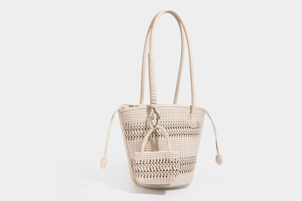Light blue open-weave woven bucket tote bag with long braided shoulder straps, drawstring side ties, and attached mini pouch