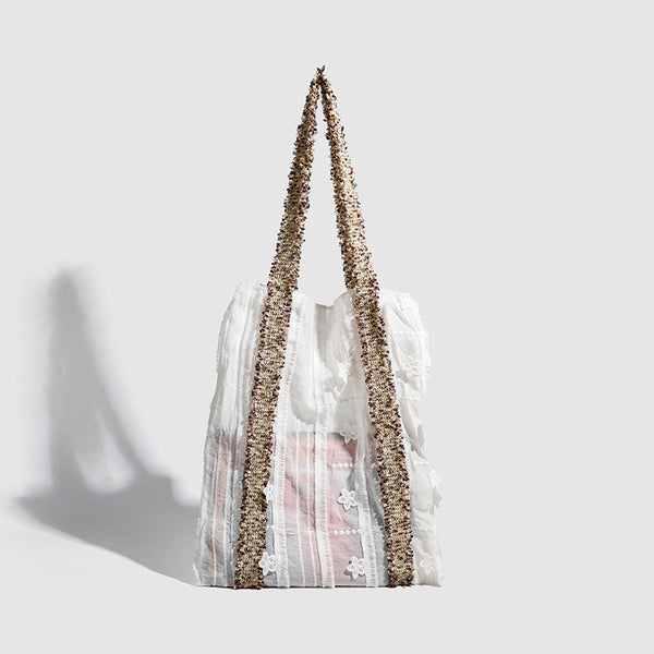 Offwhitefarbener weicher Canvas-Schultershopper mit offenen Seiten und braun-goldfarbenen Jacquard-Gurtbändern mit Blumenmuster, lässig rechteckige Form, Vorderansicht