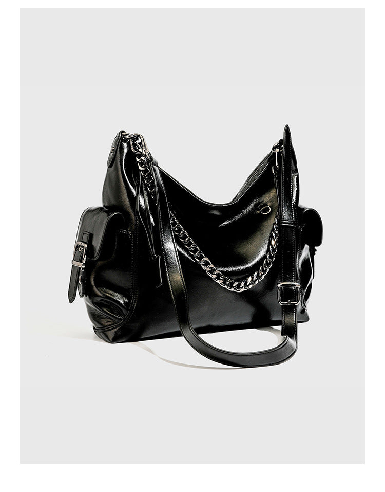 Slouchy hobo shoulder bag with glossy leather-look finish, silver-tone chain drape across front, side buckle pockets, and