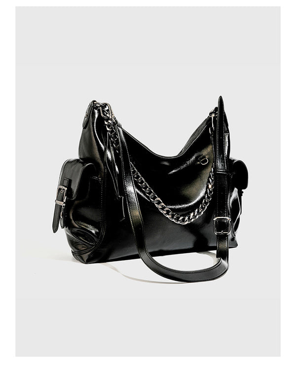 Slouchy hobo shoulder bag with glossy leather-look finish, silver-tone chain drape across front, side buckle pockets, and