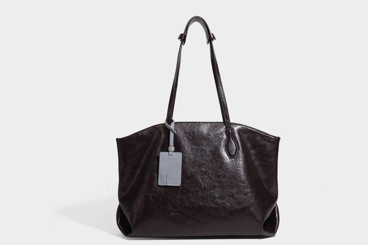 Übergroße, lässig fallende Tote-Bag aus glänzendem, geknittertem Lederimitat in dunklem Burgunderrot mit zwei langen Schulterriemen und kontrastierendem