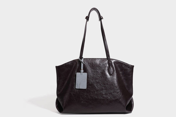 Übergroße, lässig fallende Tote-Bag aus glänzendem, geknittertem Lederimitat in dunklem Burgunderrot mit zwei langen Schulterriemen und kontrastierendem