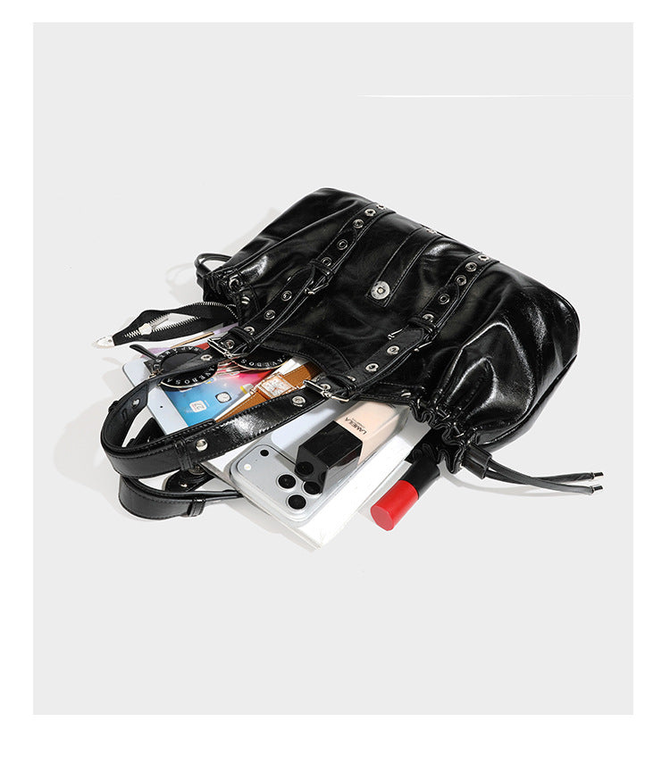 Large black glossy leather-look tote bag with silver buckle straps, eyelet grommet panels, drawstring side gathers, and