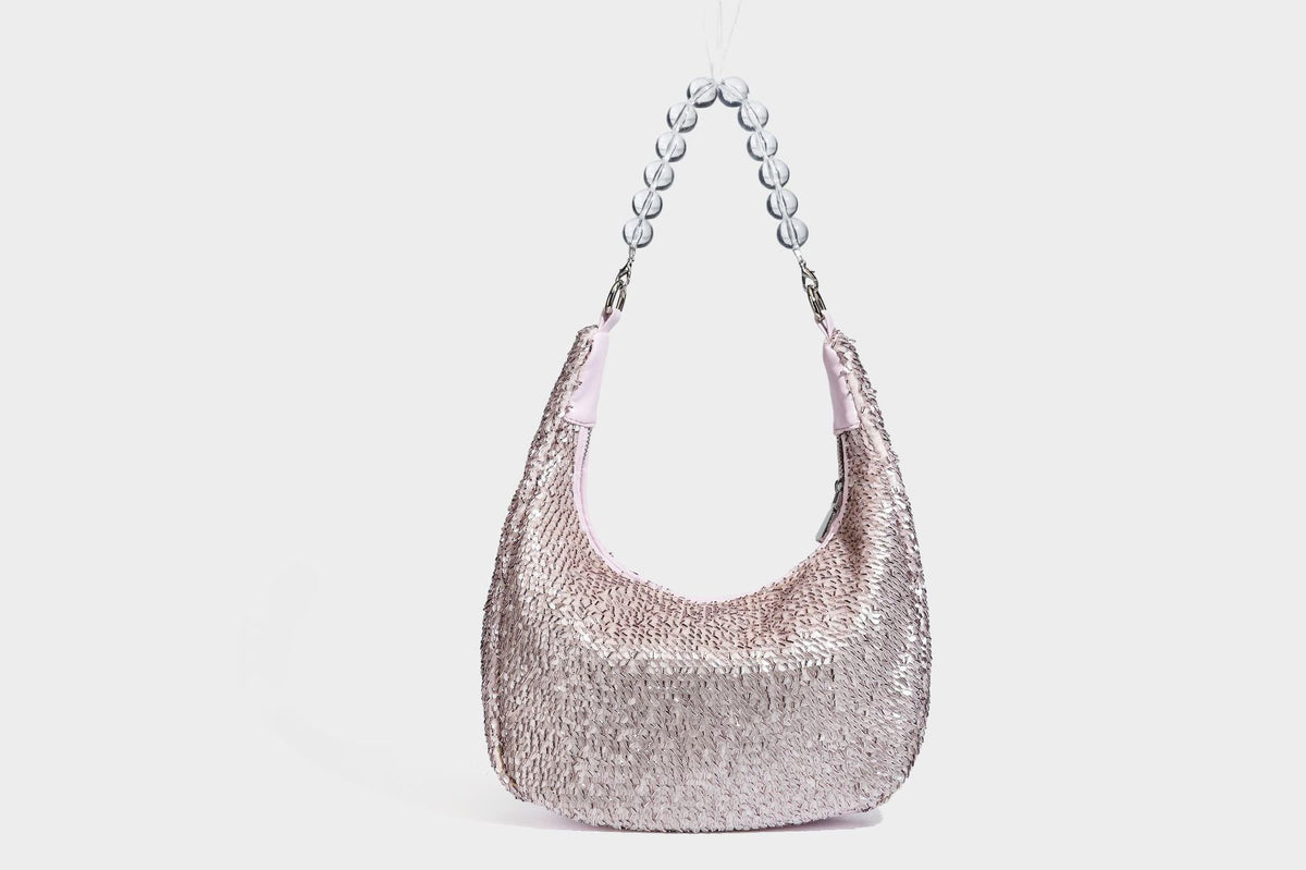 Kleine sichelförmige Schultertasche mit vollständig mit silberfarbenen Pailletten besetzter Außenseite, transparentem Henkel aus kugelförmigen Perlen und Reißverschluss in Silberoptik