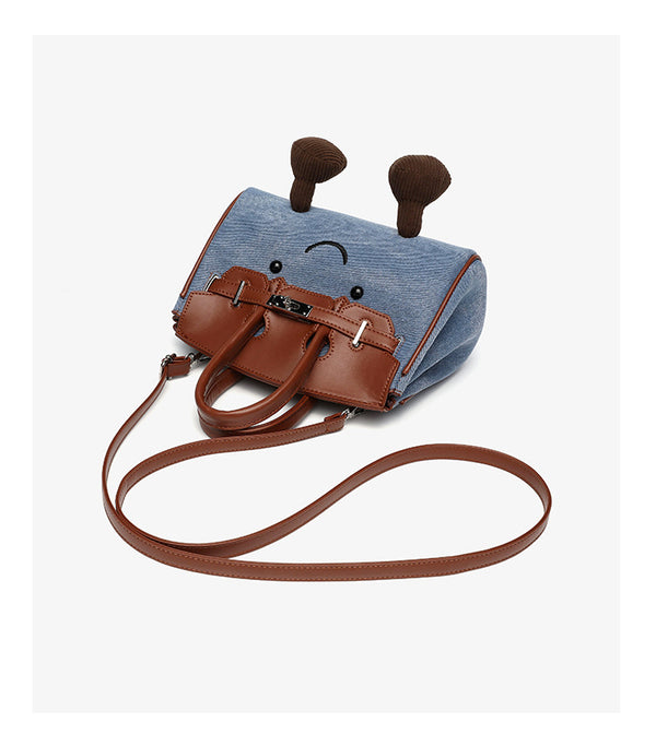 Small structured trapezoid satchel bag with smiling face motif, pom-pom accents, brown leather-look trim, silver-tone, detail