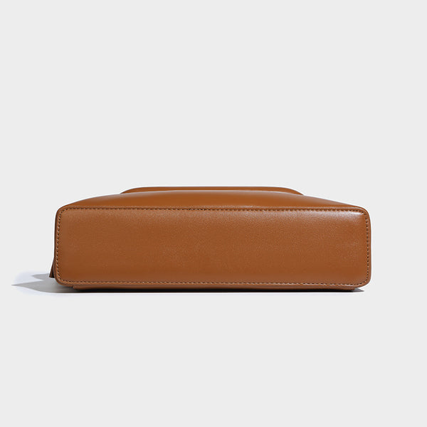 Compact structured baguette shoulder bag with smooth leather-look finish, zip top, and adjustable silver-buckle strap, detail