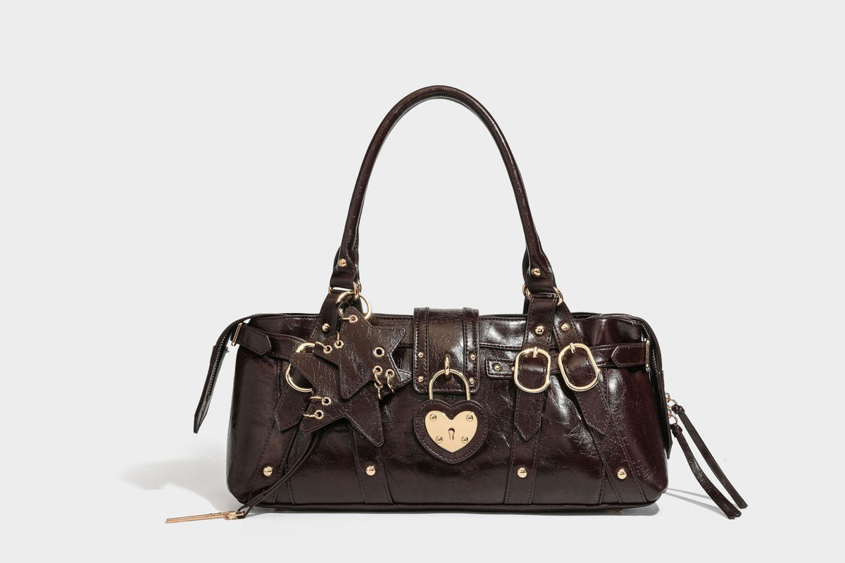 Glossy dark brown structured Boston satchel with heart-shaped lock charm, star pendant, rivet studs, multi-strap front panel