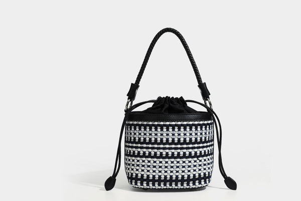 Small structured woven checker bucket bag with braided top handle, drawstring closure, and silver-tone hardware in black