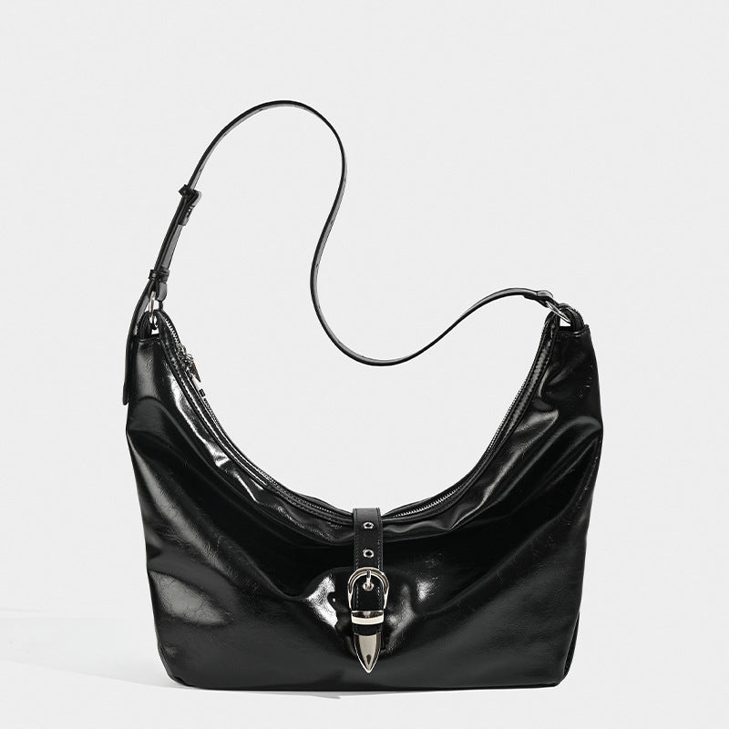 Slouchy crescent hobo bag with glossy leather-look finish, silver-tone buckle hardware, and flat shoulder strap, detail view