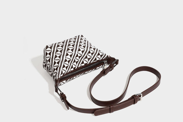 Kleine schwarz-weiße Schultertasche mit gewebtem geometrischem Muster, glatter dunkelbrauner Besatz aus Lederoptik, geknotetem verstellbarem Riemen und seitlichem