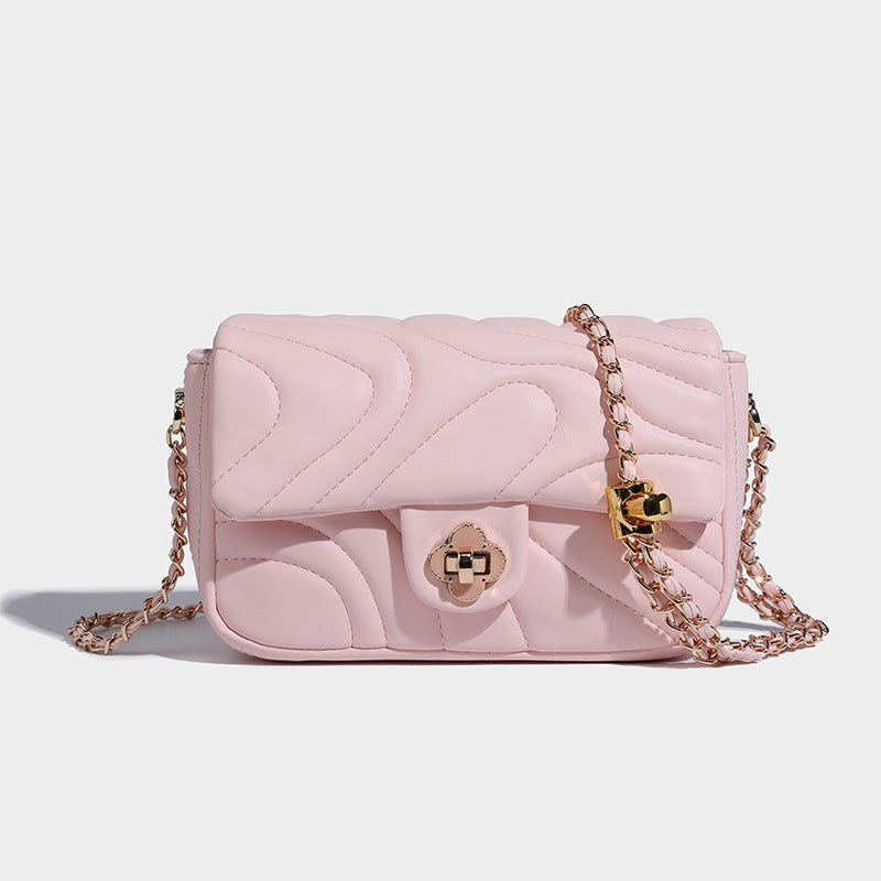 Compact cream quilted flap crossbody bag with wave stitching, gold-tone chain strap, and four-petal turn-lock clasp, detail